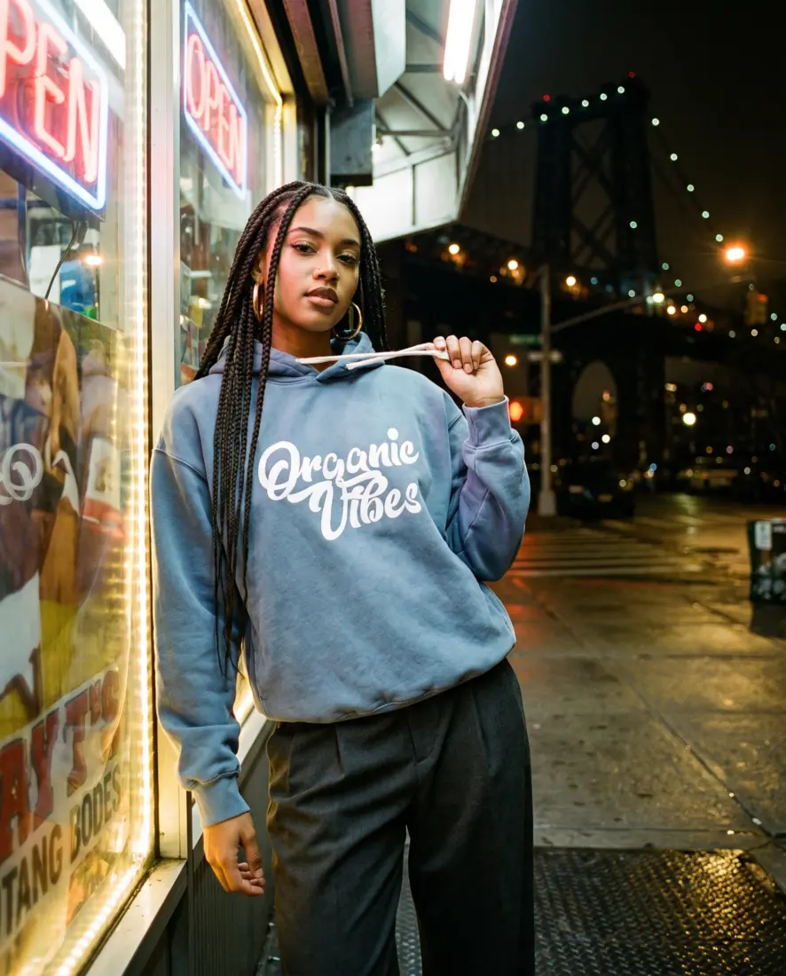 Model in the Blue Jean hoodie outside a Brooklyn bodega at night